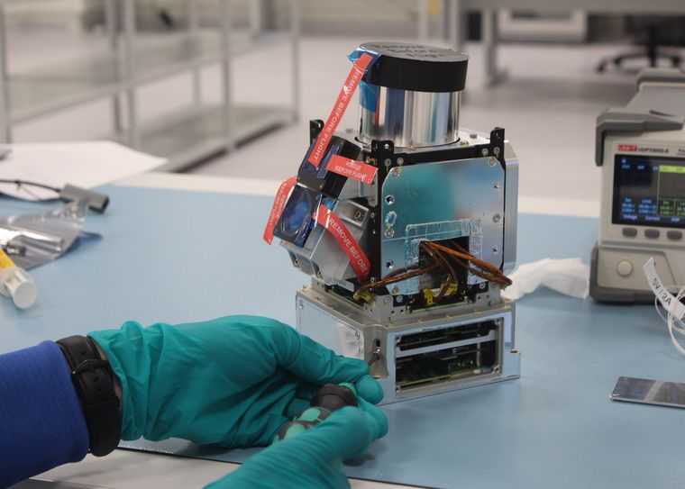 Gloved hands tightening a screw on an integrated payload module