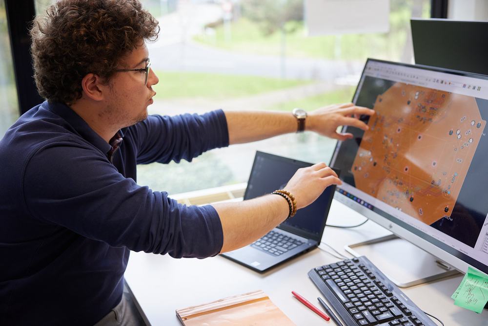 Engineer pointing at a circuit board design on a screen