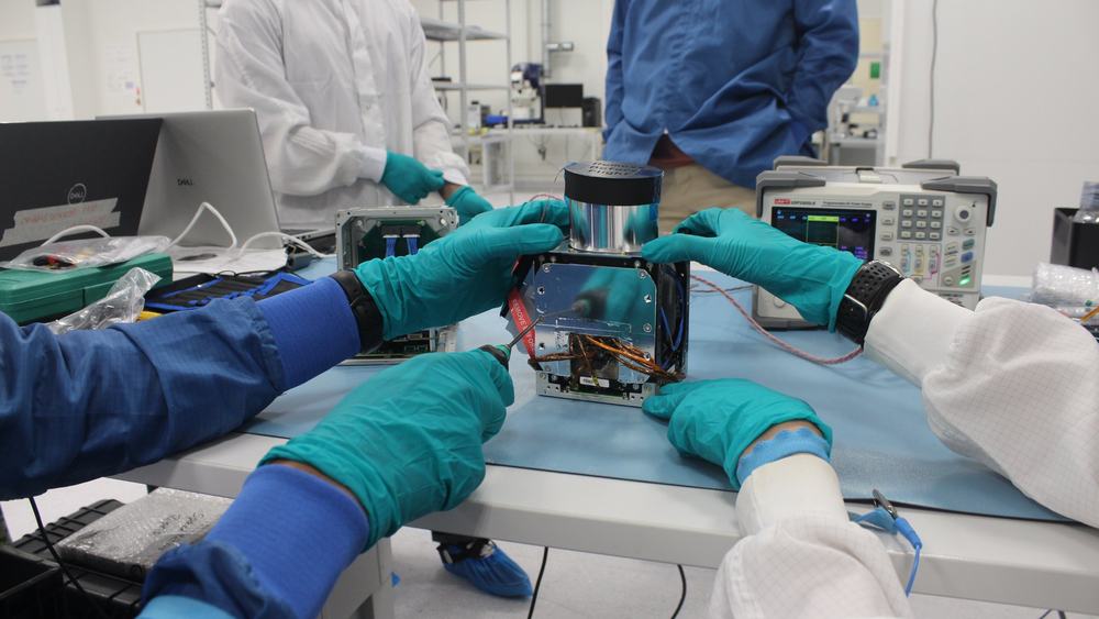Engineers integrating a payload in a clean room